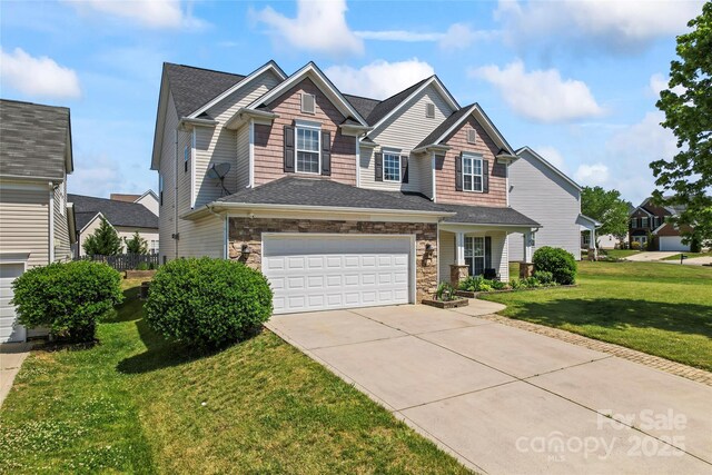 craftsman-style house with driveway, a front lawn, stone siding, and an attached garage