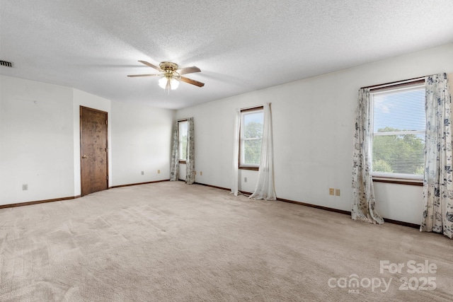 spare room featuring healthy amount of natural light, ceiling fan, a textured ceiling, carpet flooring, and baseboards