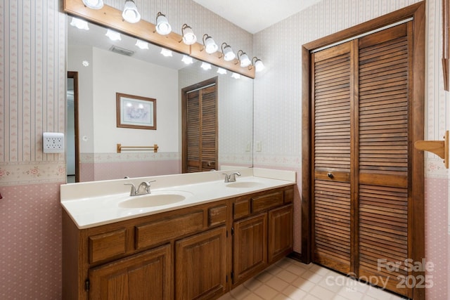 full bath featuring wallpapered walls, double vanity, a closet, and tile patterned flooring