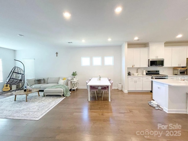 living area with light wood-type flooring, recessed lighting, and baseboards