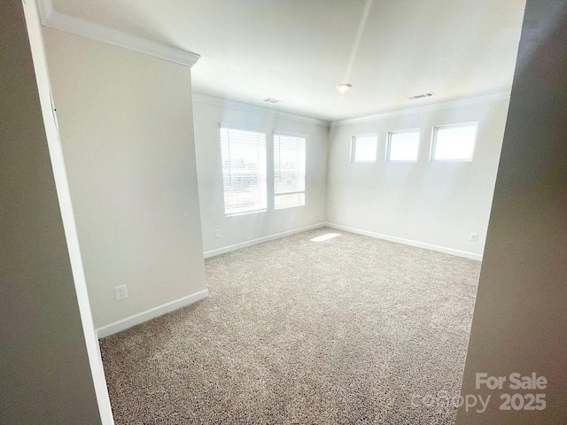 empty room with ornamental molding, carpet floors, and baseboards