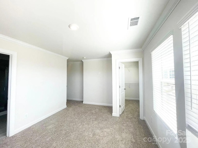 unfurnished bedroom with carpet, ornamental molding, baseboards, a spacious closet, and a closet