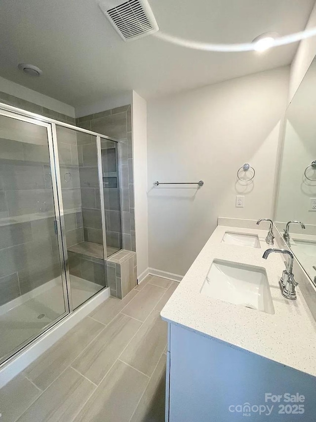 bathroom with a stall shower, double vanity, and baseboards