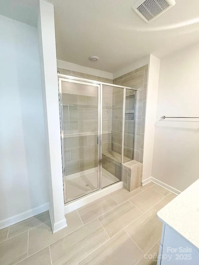 full bath with a stall shower, baseboards, and tile patterned floors
