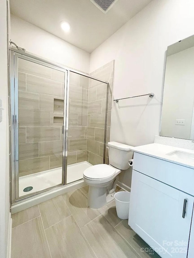 full bathroom with a stall shower, toilet, and vanity
