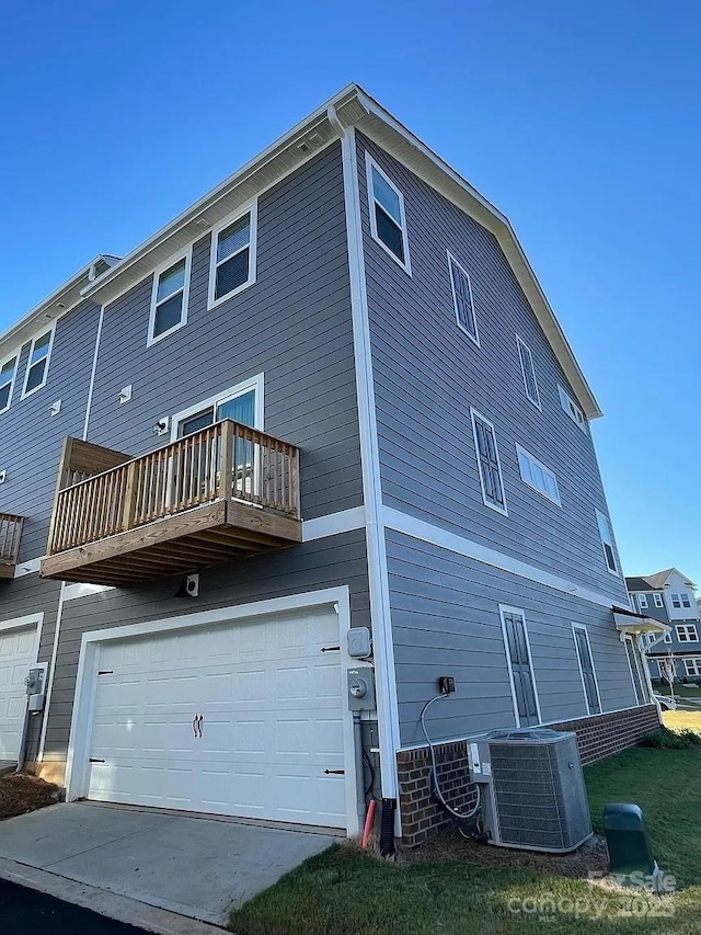 rear view of house featuring cooling unit, an attached garage, and a balcony