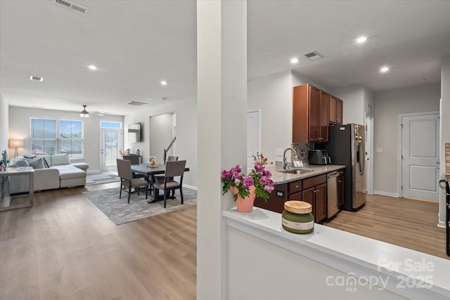 kitchen with appliances with stainless steel finishes, light wood-type flooring, a sink, a ceiling fan, and recessed lighting