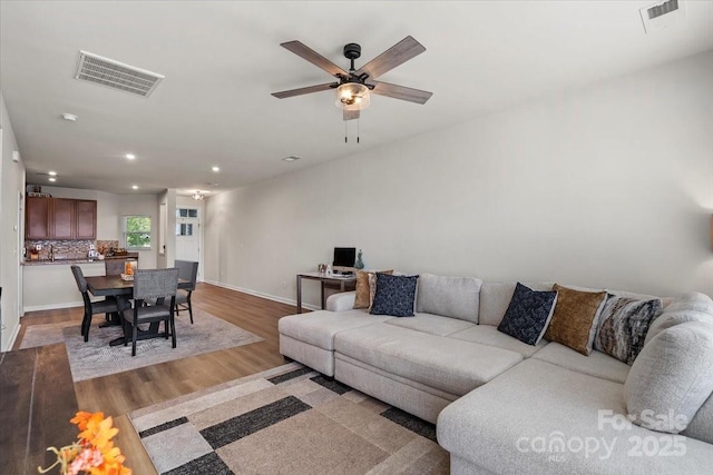 living area with light wood-style floors, recessed lighting, ceiling fan, and baseboards