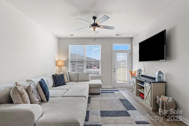 living area featuring a ceiling fan, wood finished floors, and baseboards