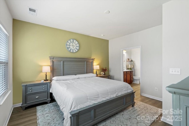 bedroom featuring wood finished floors, baseboards, and connected bathroom