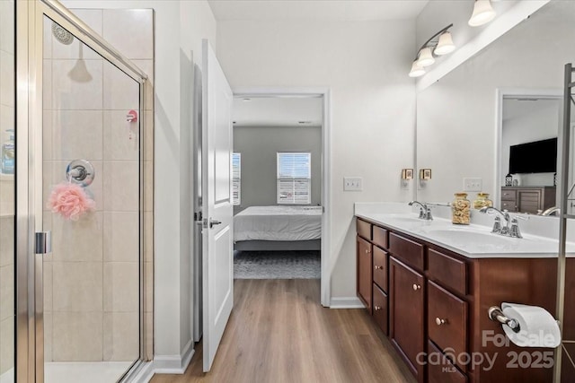 bathroom featuring ensuite bath, wood finished floors, a shower stall, double vanity, and baseboards