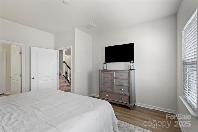 bedroom with wood finished floors, multiple windows, and baseboards