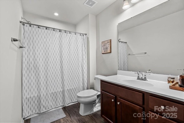 bathroom with wood finished floors, vanity, toilet, and curtained shower