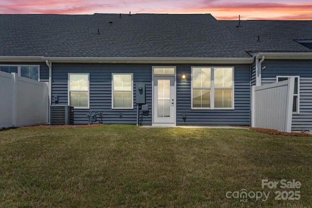 back of property at dusk featuring a shingled roof