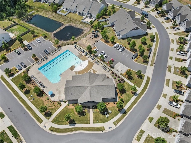 aerial perspective of suburban area featuring a pool and a large body of water