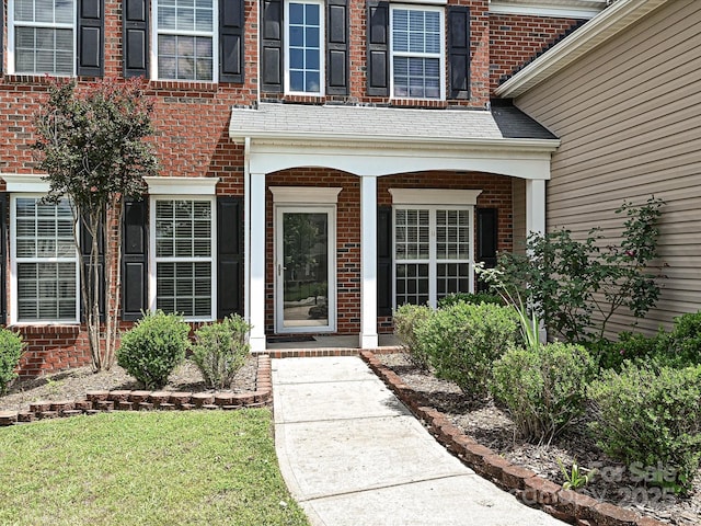 property entrance featuring brick siding and a porch