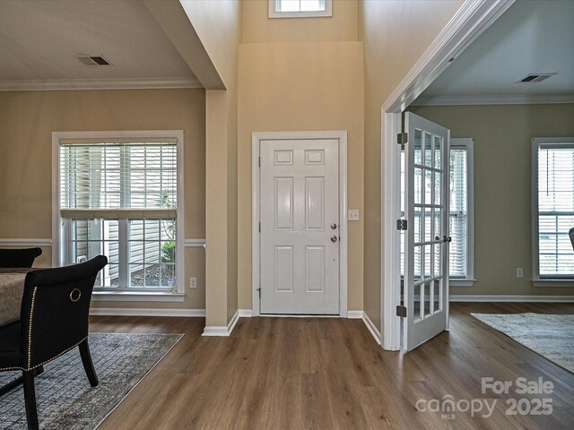 entrance foyer featuring wood finished floors, healthy amount of natural light, baseboards, and ornamental molding