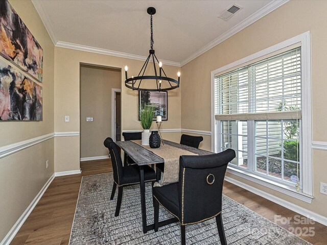 dining area featuring a chandelier, dark wood-type flooring, crown molding, and baseboards