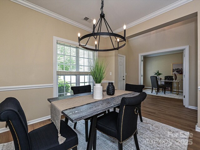 dining area featuring a chandelier, wood finished floors, ornamental molding, and baseboards