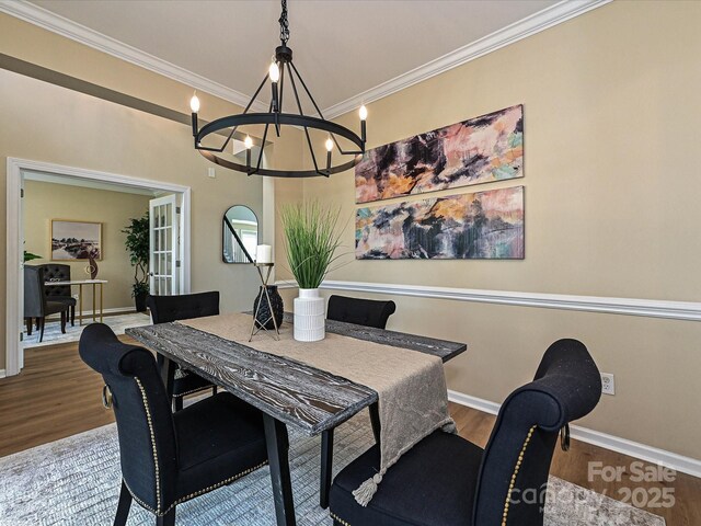 dining space with wood finished floors, a chandelier, crown molding, and baseboards
