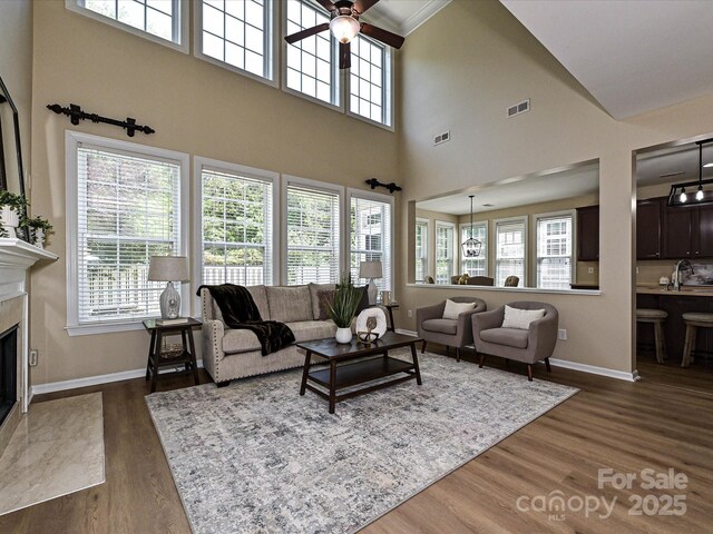 living room with dark wood-type flooring, baseboards, plenty of natural light, and a towering ceiling