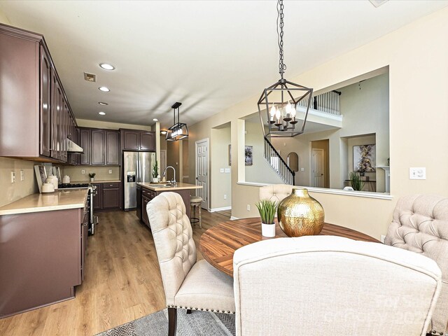 dining space with a chandelier, wood finished floors, recessed lighting, stairway, and baseboards