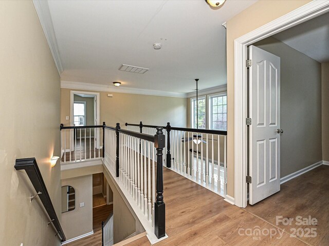 staircase featuring crown molding, wood finished floors, and baseboards