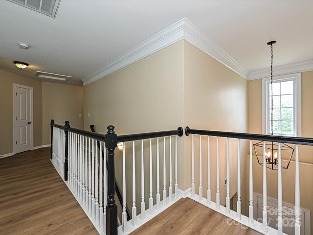 stairway featuring wood finished floors, crown molding, a chandelier, and baseboards