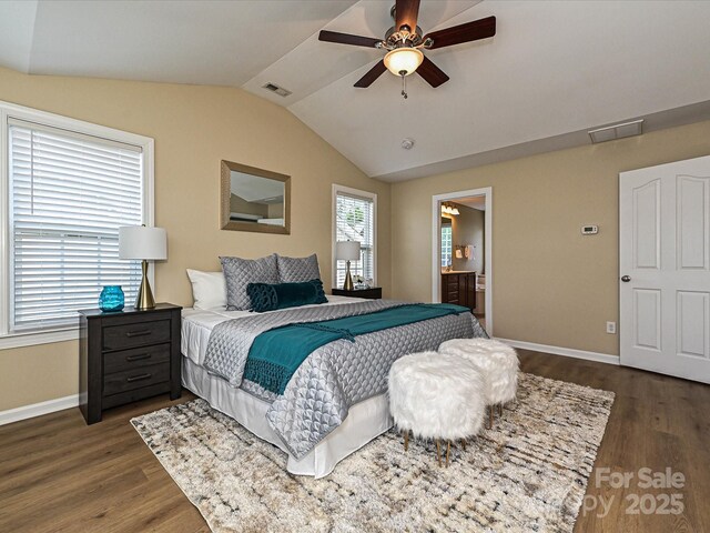 bedroom with vaulted ceiling, dark wood finished floors, baseboards, ensuite bath, and ceiling fan
