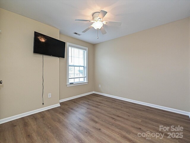unfurnished room with dark wood finished floors, baseboards, and a ceiling fan