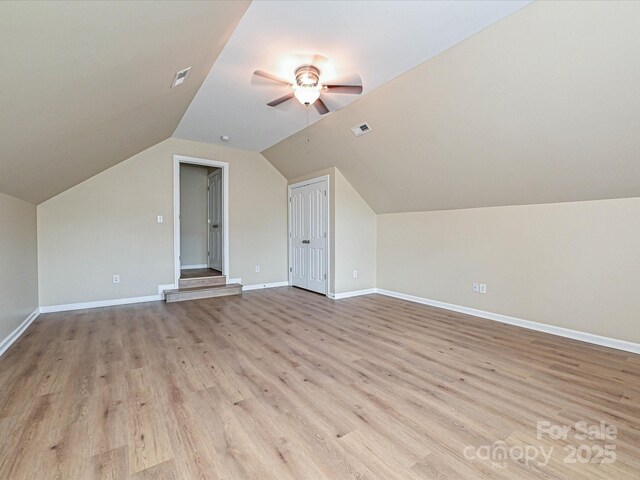 additional living space with ceiling fan, light wood-style flooring, baseboards, and lofted ceiling