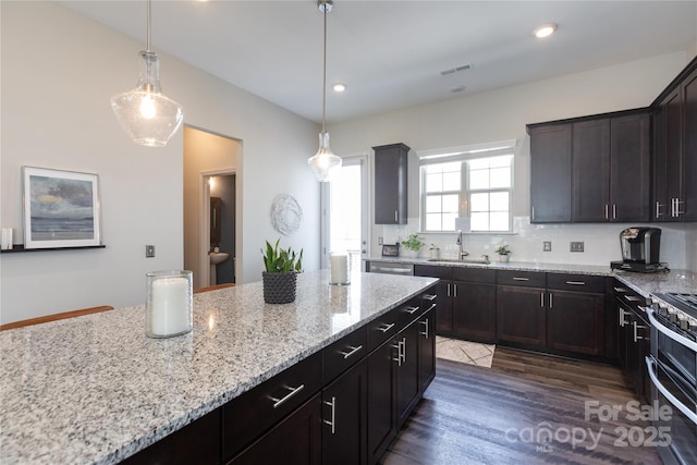 9521 Ainslie Downs St, Charlotte, NC 28273 - kitchen featuring light stone countertops, dark wood-style flooring, stainless steel appliances, decorative backsplash, and decorative light fixtures