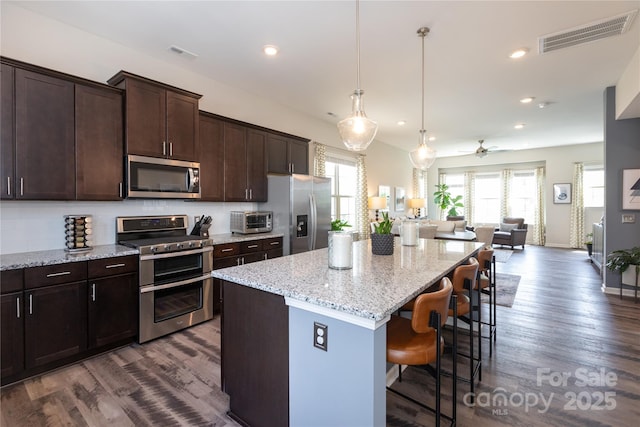9521 Ainslie Downs St, Charlotte, NC 28273 - kitchen with appliances with stainless steel finishes, open floor plan, dark wood-style flooring, a kitchen breakfast bar, and recessed lighting