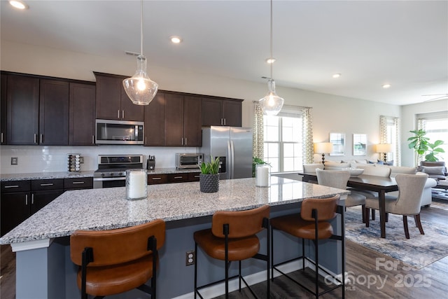 9521 Ainslie Downs St, Charlotte, NC 28273 - kitchen with stainless steel appliances, dark wood-style floors, a center island, open floor plan, and a kitchen breakfast bar