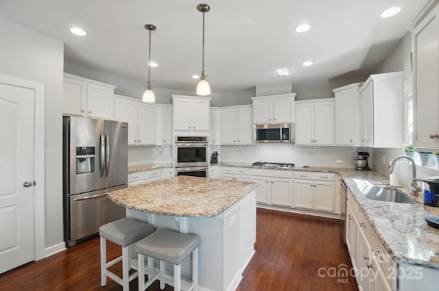 16831 Alydar Commons Ln, Charlotte, NC 28278 - kitchen featuring appliances with stainless steel finishes, a kitchen island, white cabinets, dark wood-type flooring, and recessed lighting