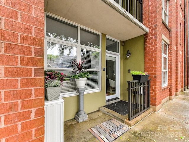 view of exterior entry featuring stucco siding and brick siding