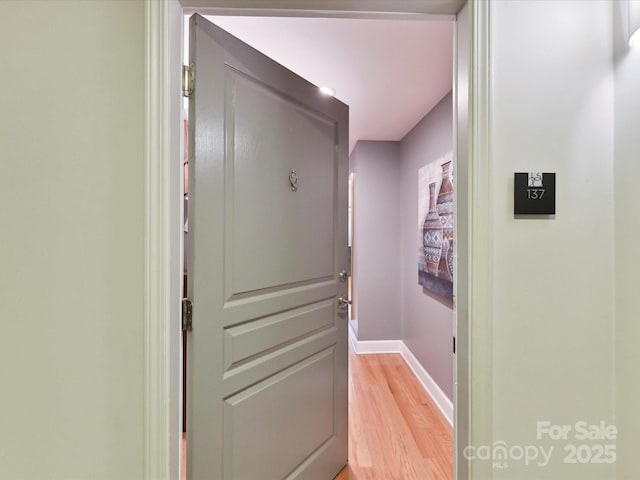 hall with baseboards and light wood-style floors