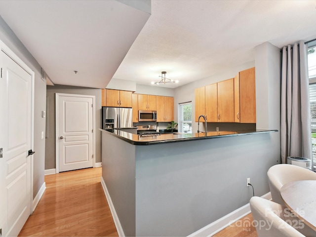 kitchen with appliances with stainless steel finishes, baseboards, dark countertops, and plenty of natural light