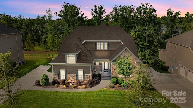 craftsman-style house with stone siding, driveway, and a front yard