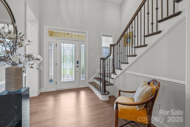 entrance foyer with wood finished floors, stairway, a high ceiling, and baseboards
