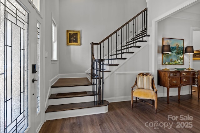 entrance foyer featuring wood finished floors, stairs, baseboards, and a high ceiling