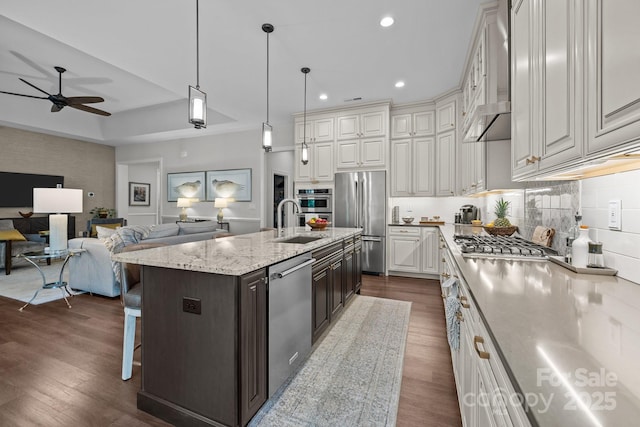 kitchen with appliances with stainless steel finishes, a ceiling fan, a sink, white cabinetry, and backsplash