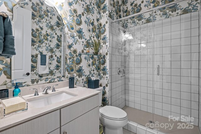 full bath with a stall shower, toilet, vanity, and wallpapered walls