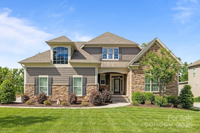 view of front of property with stone siding, a shingled roof, a front yard, and a standing seam roof
