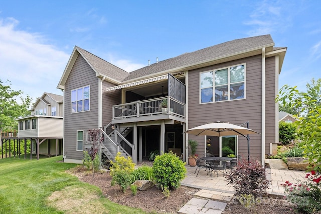 rear view of house featuring stairs, a patio area, a yard, a deck, and roof with shingles