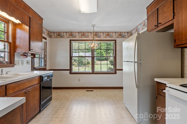 1940 12th St NE, Hickory, NC 28601 - kitchen with wallpapered walls, black dishwasher, a chandelier, light countertops, and brown cabinetry