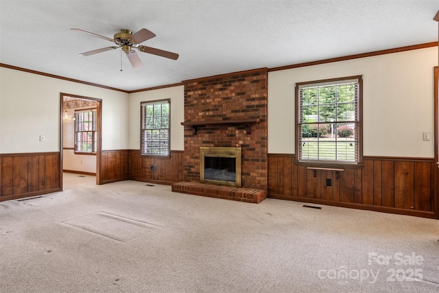 1940 12th St NE, Hickory, NC 28601 - unfurnished living room with a wainscoted wall, wood walls, a ceiling fan, a brick fireplace, and carpet floors
