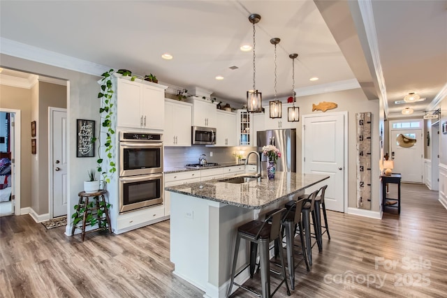 kitchen featuring a sink, appliances with stainless steel finishes, a kitchen breakfast bar, glass insert cabinets, and dark stone counters