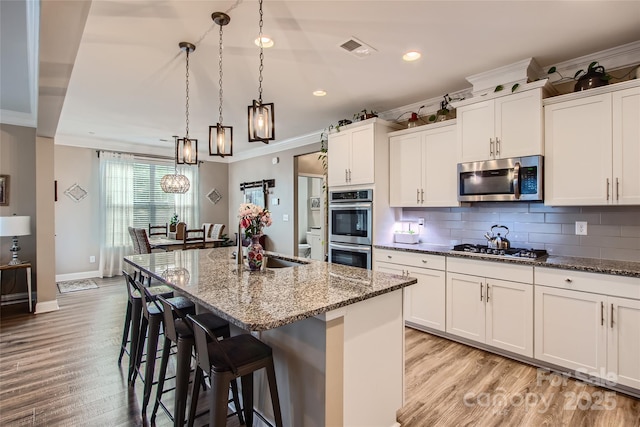 kitchen with stainless steel appliances, crown molding, light wood finished floors, recessed lighting, and decorative backsplash