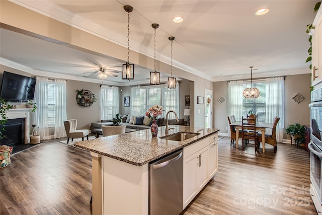 kitchen featuring a sink, a fireplace, open floor plan, dishwasher, and ornamental molding